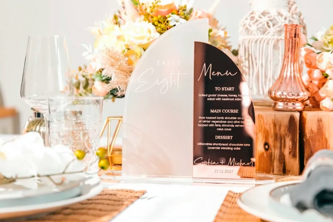 a table setting with a menu sign in the center, surrounded by various tableware and decorations.