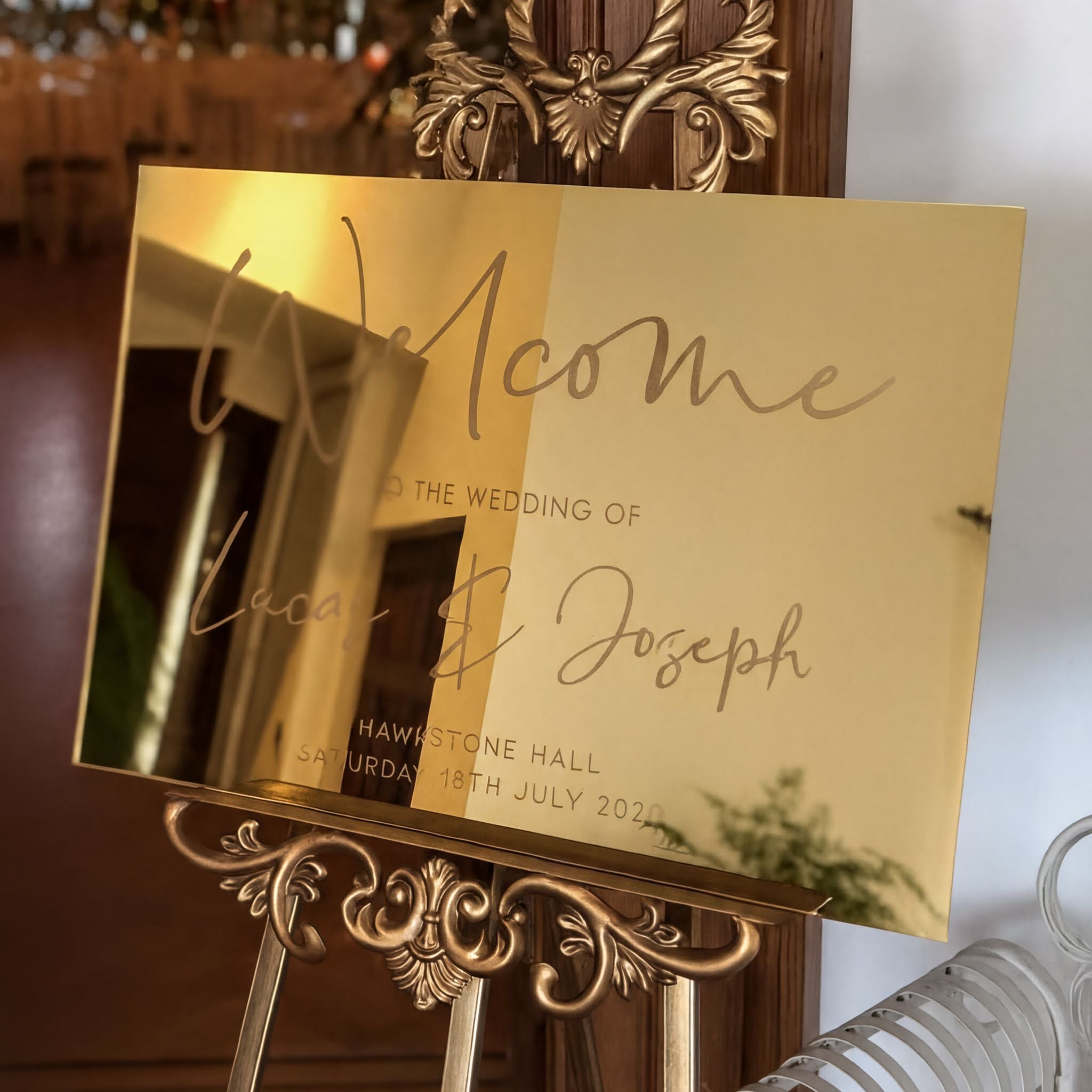 a golden wedding welcome sign with the names "Lena & Joseph" and the date "Saturday, July 18th, 2020" displayed on it.
