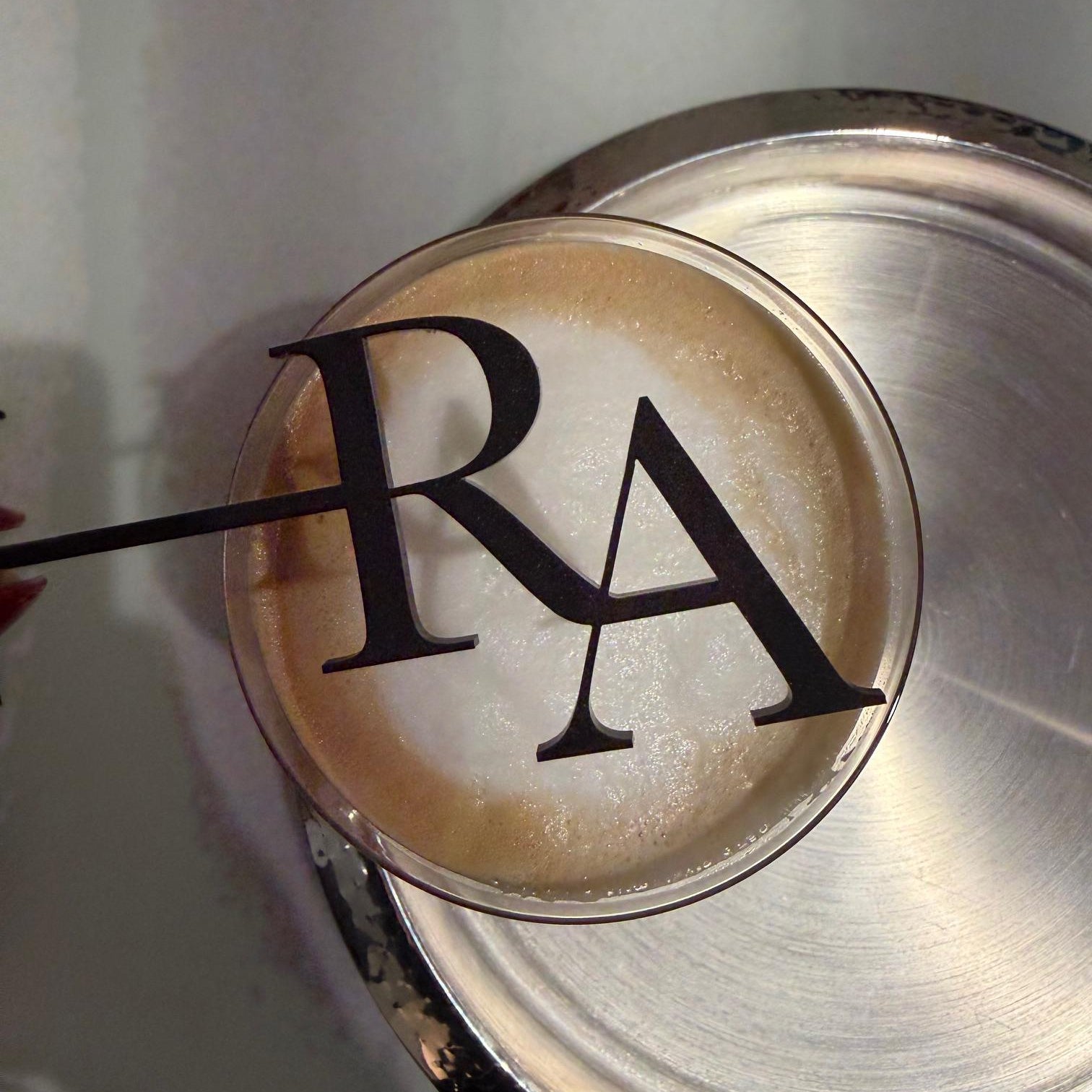 A close-up view of a glass containing a beverage, with a large black letter "A" on the glass.