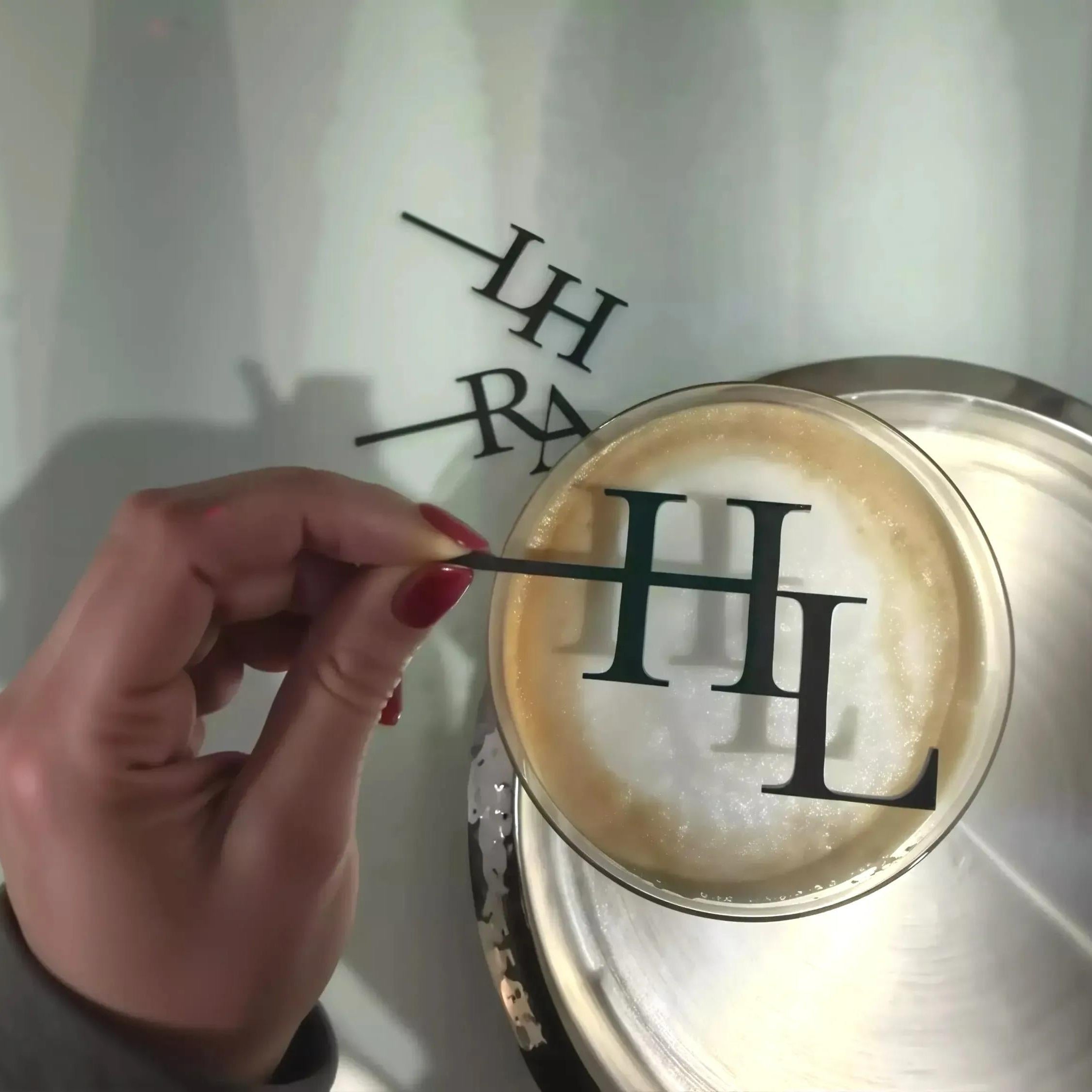 A hand holding a toothpick with the letters "LF" on it, positioned over a petri dish containing a substance.