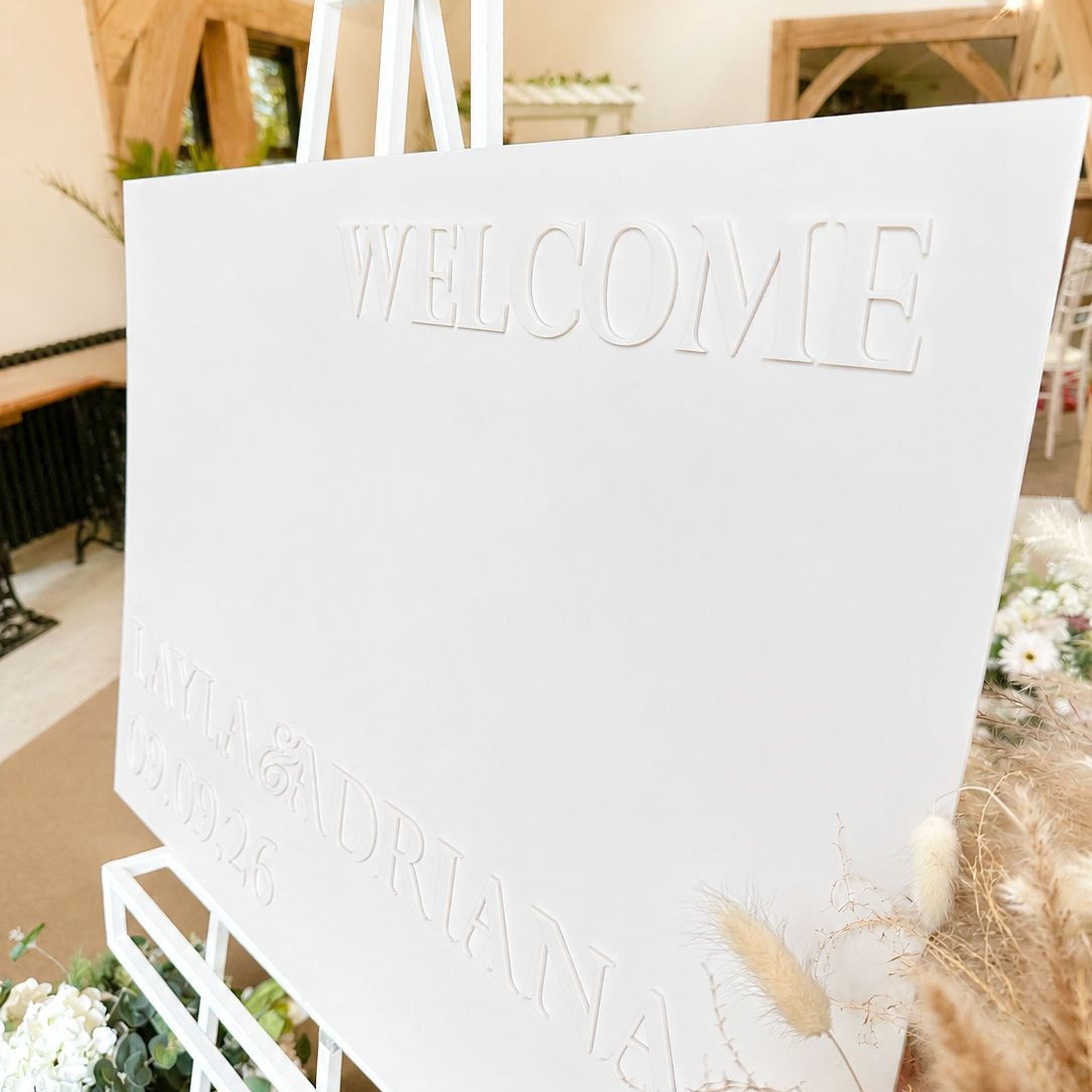 a white sign with the word "WELCOME" prominently displayed, along with the names "LAYLA & DRIANA" and the date "09.09.2026".