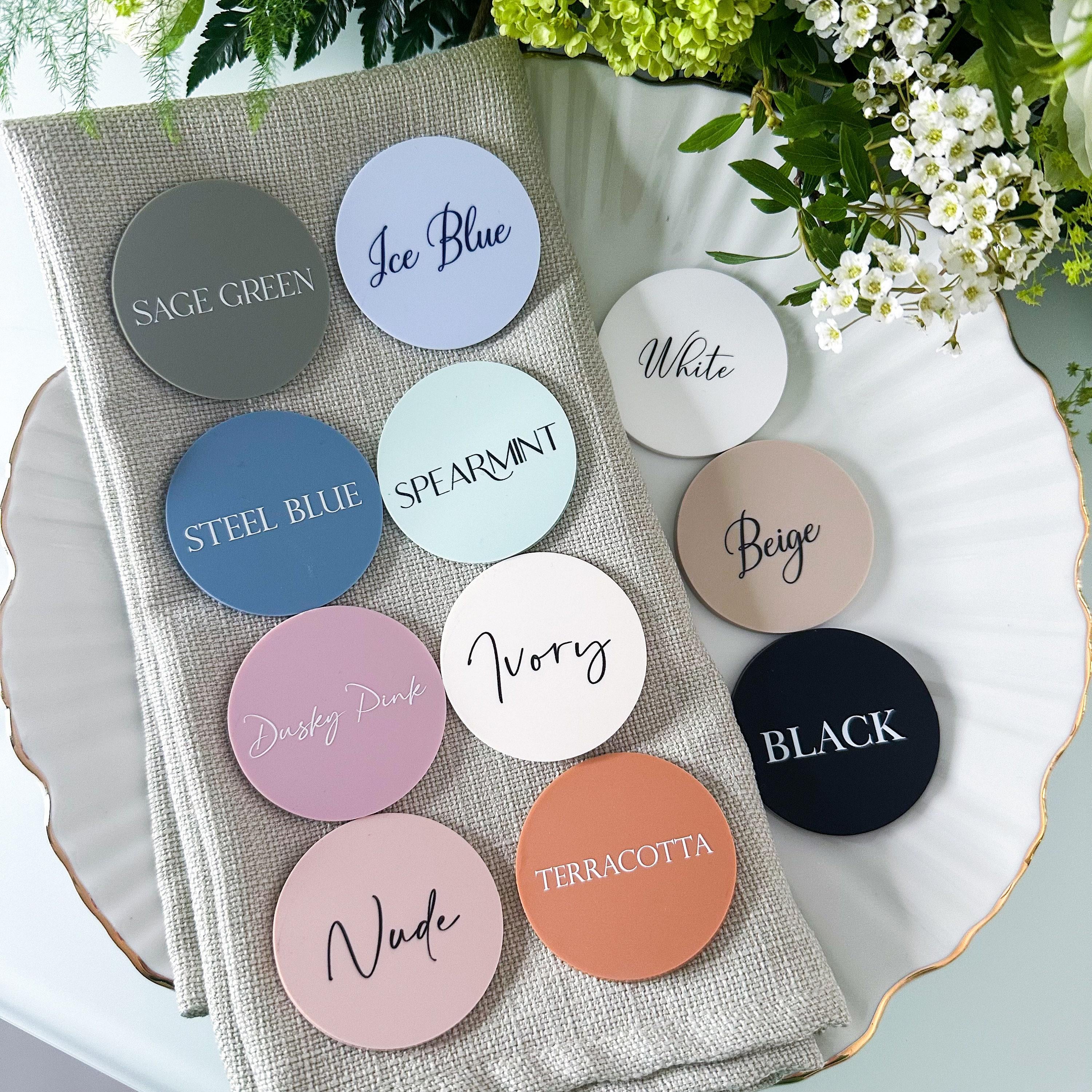 A collection of colorful coasters or stickers with names of different colors, placed on a beige cloth or napkin.