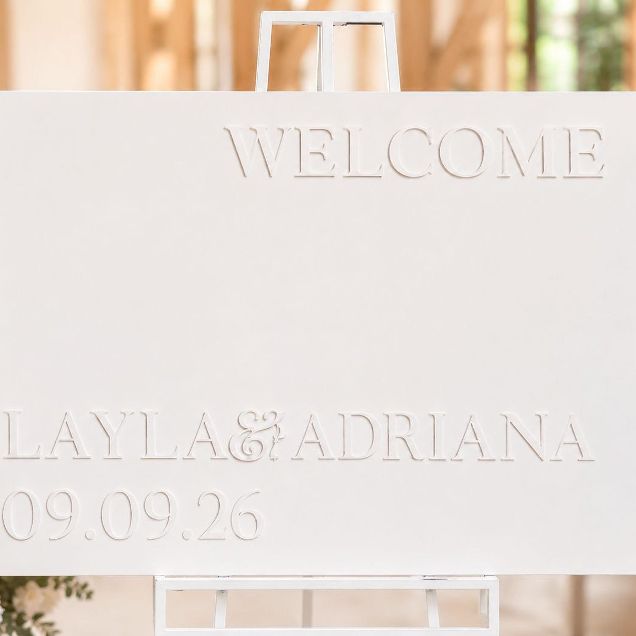 a white sign with the text "WELCOME LAYLA & ADRIANA 09.09.26" on it.
