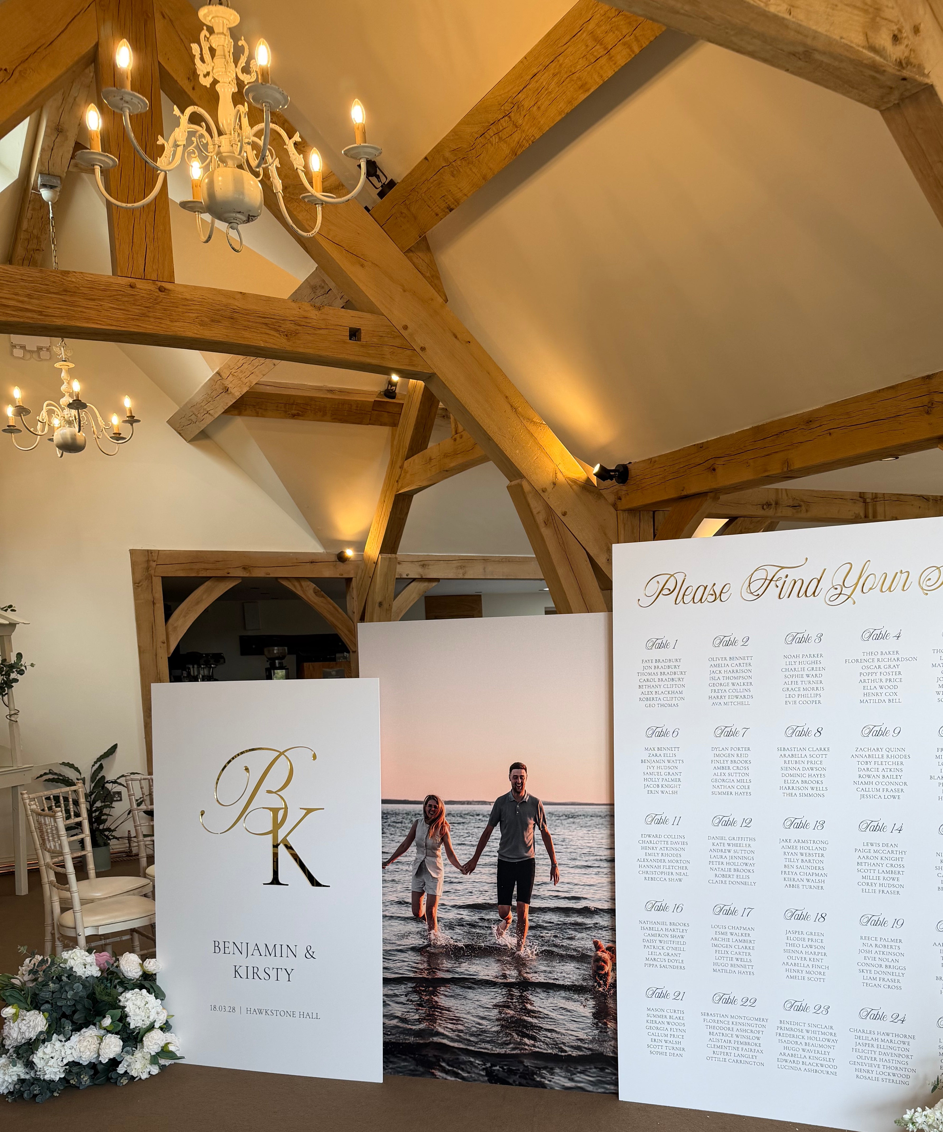 a wedding reception venue with a wooden ceiling and a large seating chart displayed on a stand.