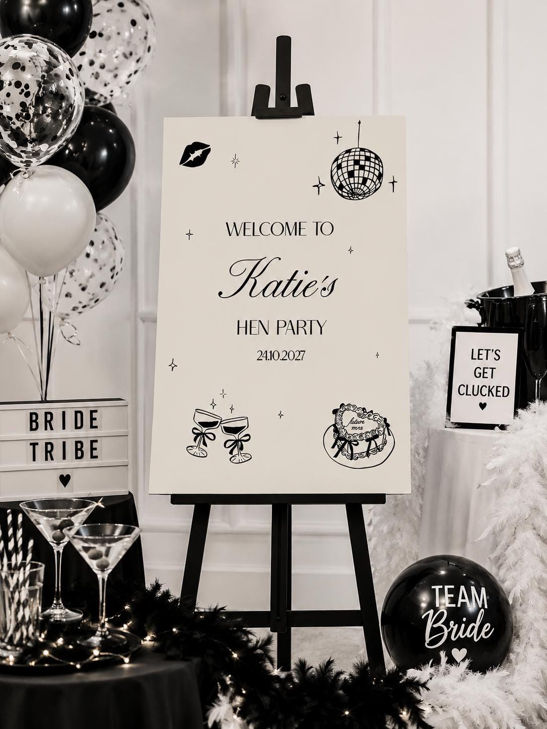 a black and white sign welcoming guests to a hen party, surrounded by various party decorations and items such as balloons, a cake, and a "TEAM Bride" sign.