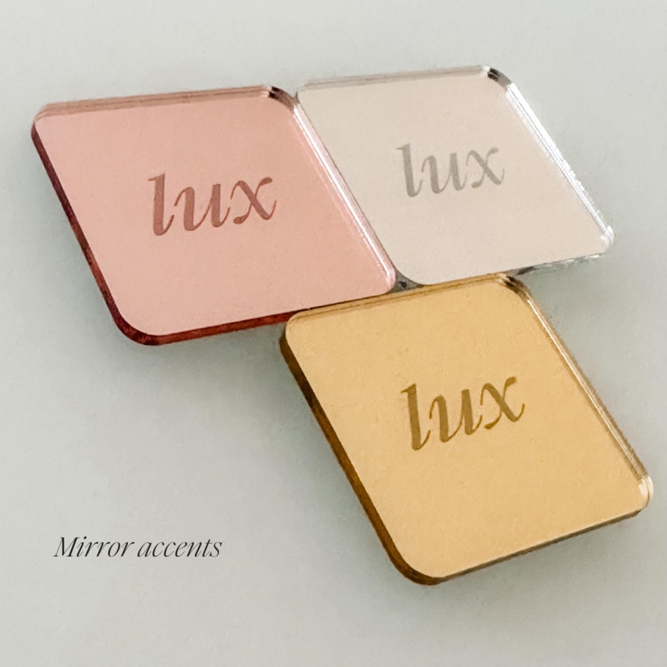 three square mirrors with the word "Lux" engraved on them, arranged in a triangular formation.