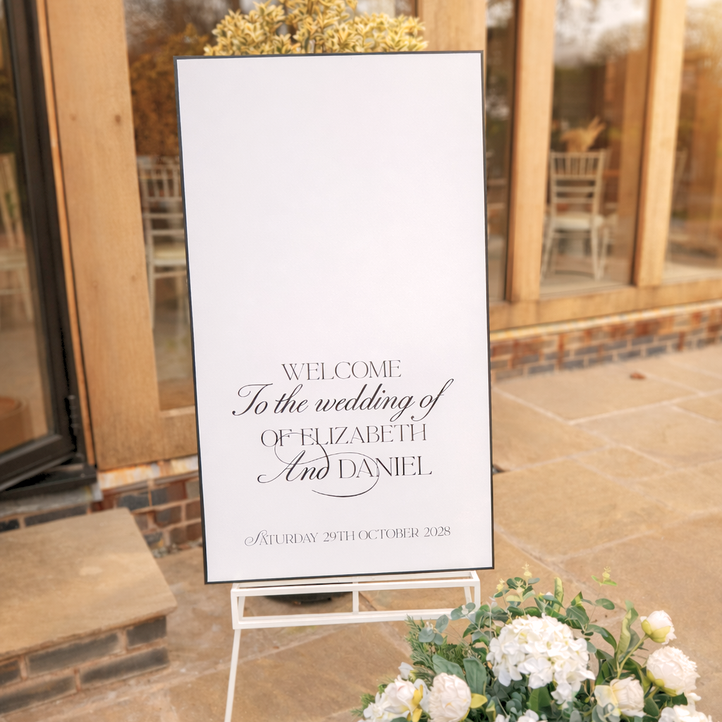 a white sign welcoming guests to the wedding of Elizabeth and Daniel, with a potted plant in the foreground.