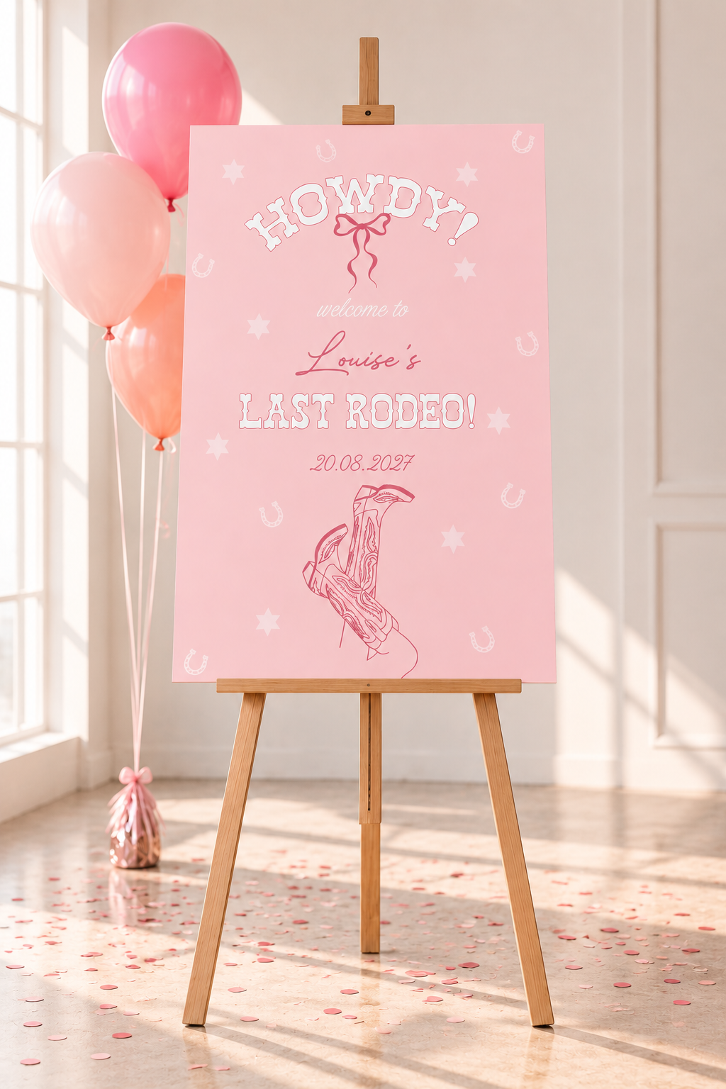 A pink sign with the text "Howdy! Welcome to Louise's Last Rodeo! 20.08.2027" is displayed on an easel, with pink and orange balloons in the background.
