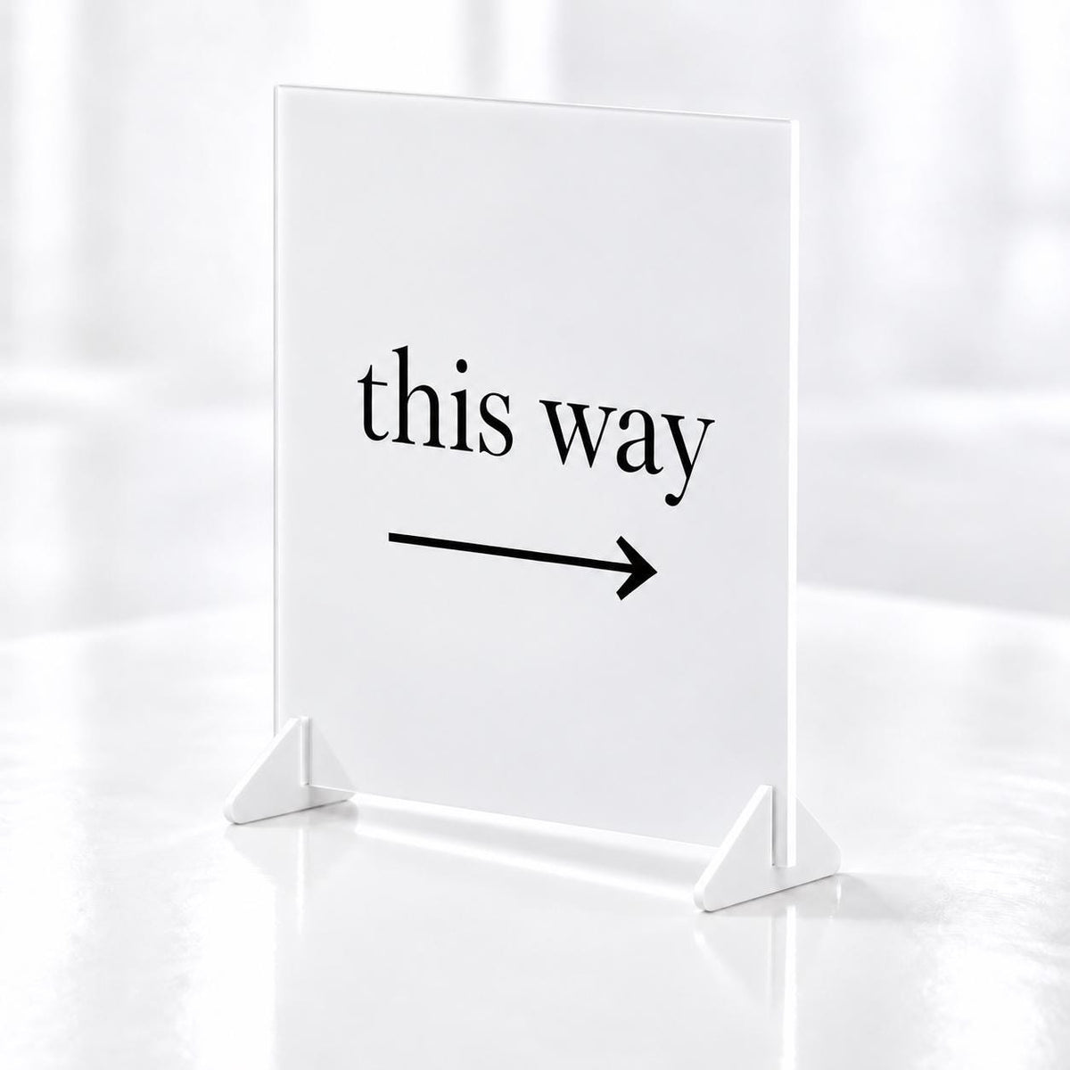 a white sign with the text "this way" and an arrow pointing to the right.
