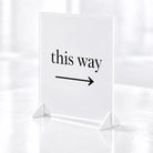 a white sign with the text "this way" and an arrow pointing to the right.