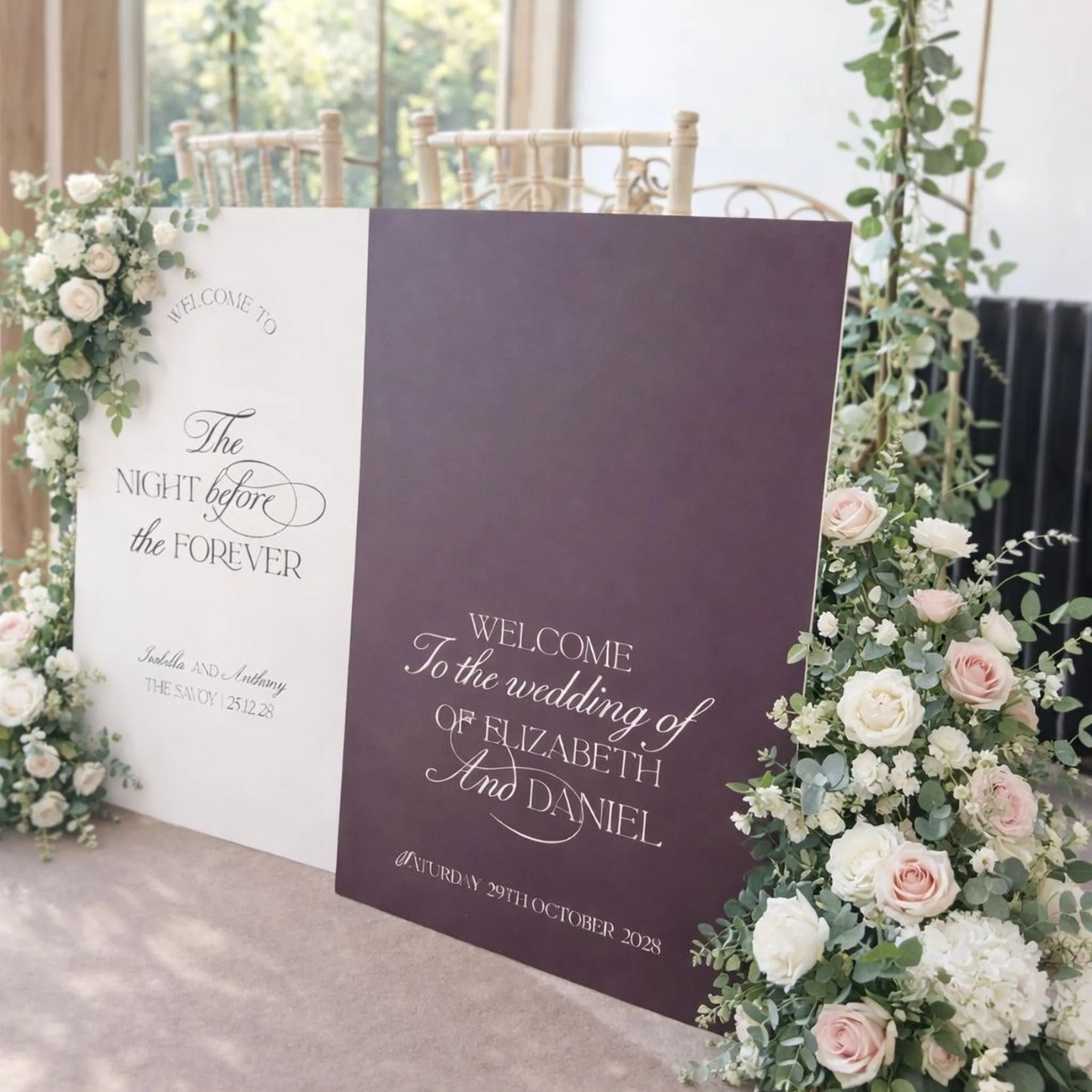 a wedding ceremony setup with two large signs welcoming guests to the wedding of Elizabeth and Daniel. The signs are adorned with white and purple flowers, and the text on the signs reads "Welcome To The Wedding Of Elizabeth And Daniel".