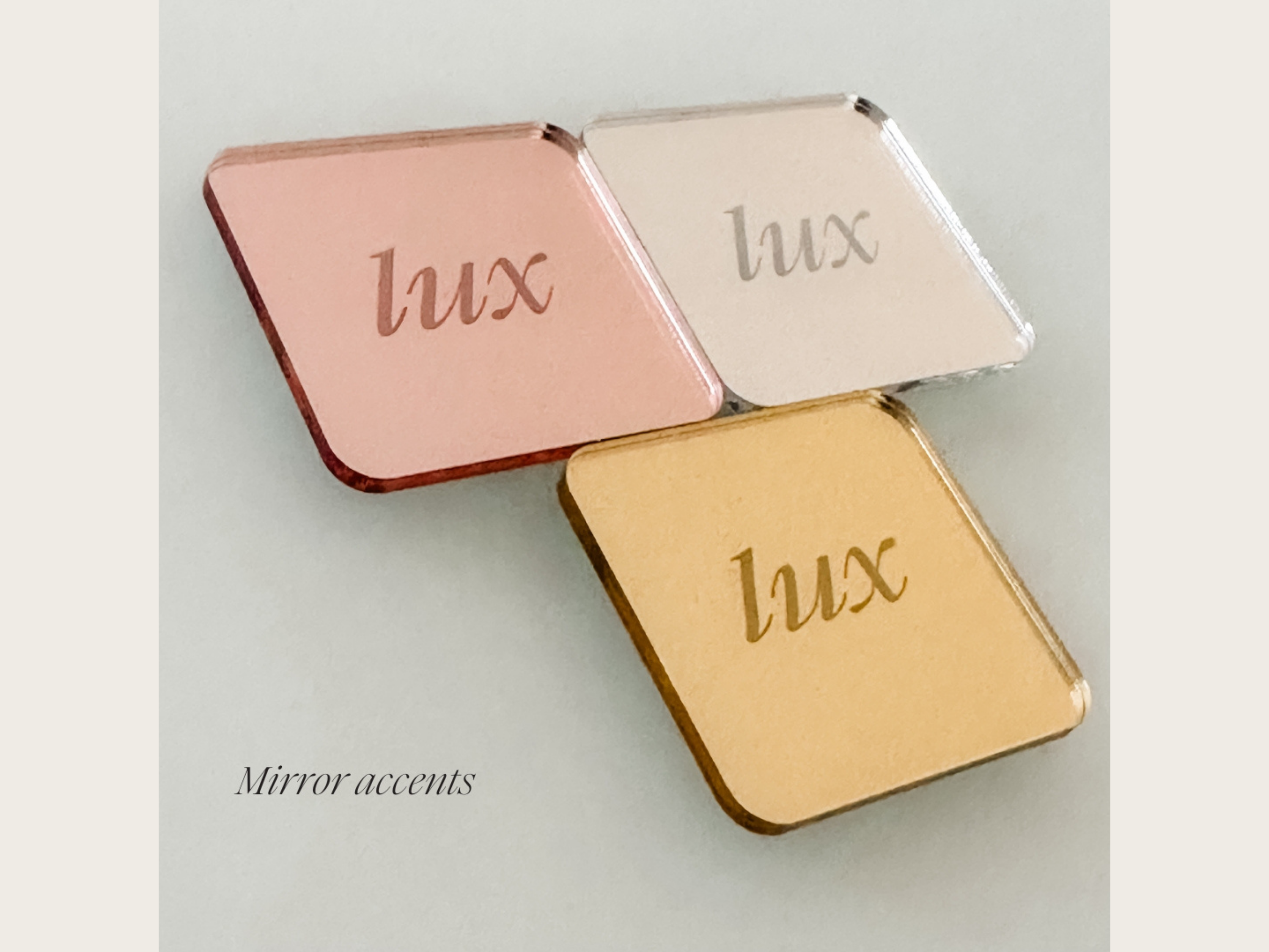 three square mirrors with the word "Lux" engraved on them, arranged in a triangular formation.