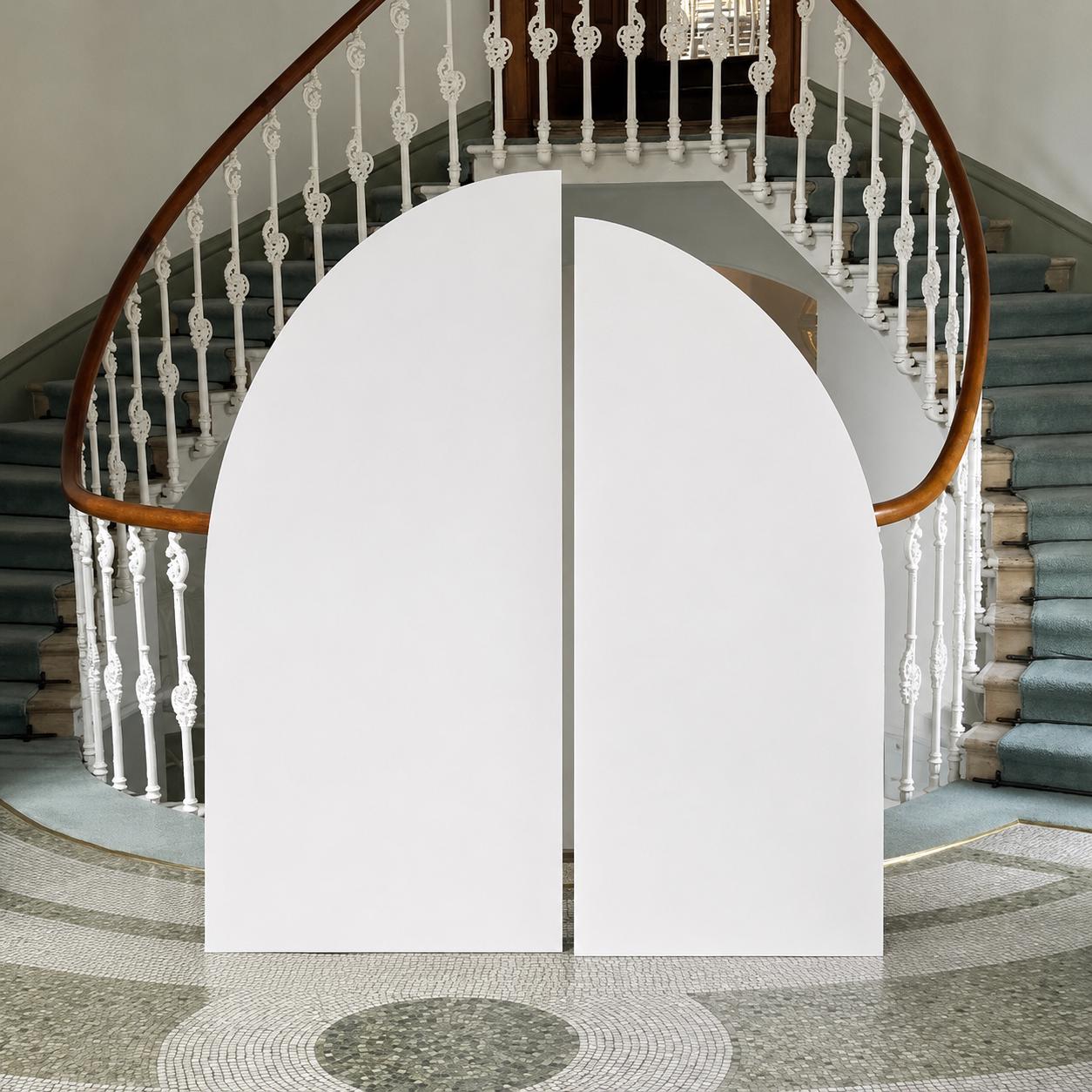 a white archway and a staircase with a wooden railing, set against a backdrop of a tiled floor and a circular pattern.