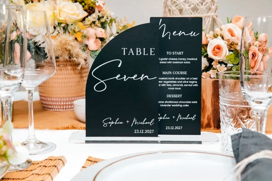 a black and white menu stand with a table setting in the background.