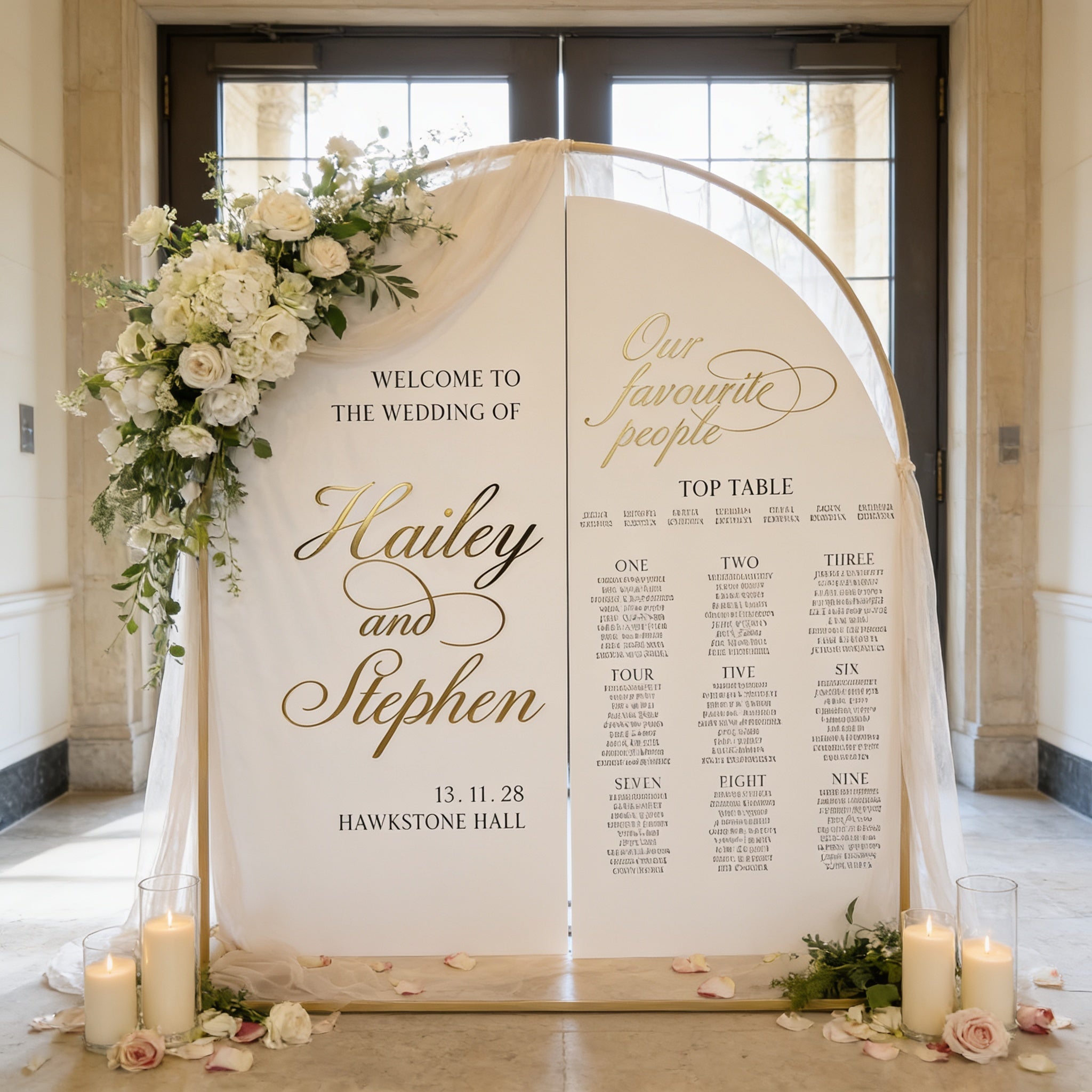 a wedding invitation sign with a floral design and seating plan. The sign is set up in a room with a white arch and candles, creating a romantic atmosphere.