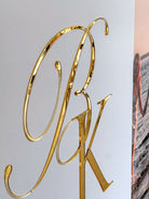a close-up view of a golden letter "P" and "K" on a white background.