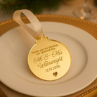 A gold-colored ornament with a ribbon attached, placed on a white plate.