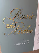 a grey background with gold text that reads "Rosa and Archie" and "13.11.28" below it.