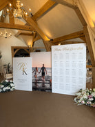 a wedding reception venue with a wooden ceiling and a large seating chart displayed on a stand.