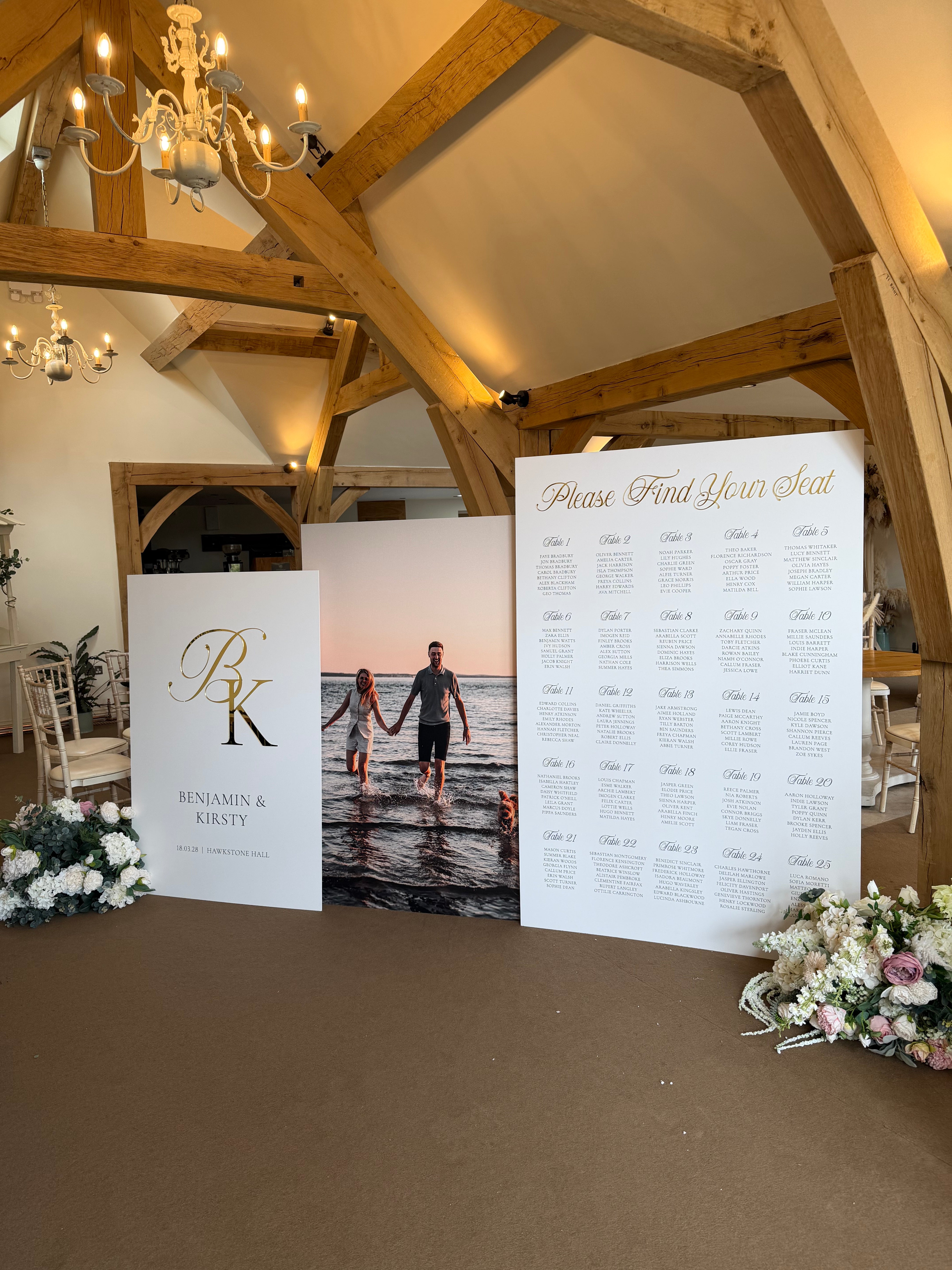 a wedding reception venue with a wooden ceiling and a large seating chart displayed on a stand.