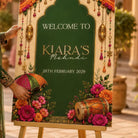 a colorful sign with decorative elements such as flowers, a drum, and a hand holding an umbrella. The sign is welcoming visitors to a party or event, with the date "28th February 2029" displayed.