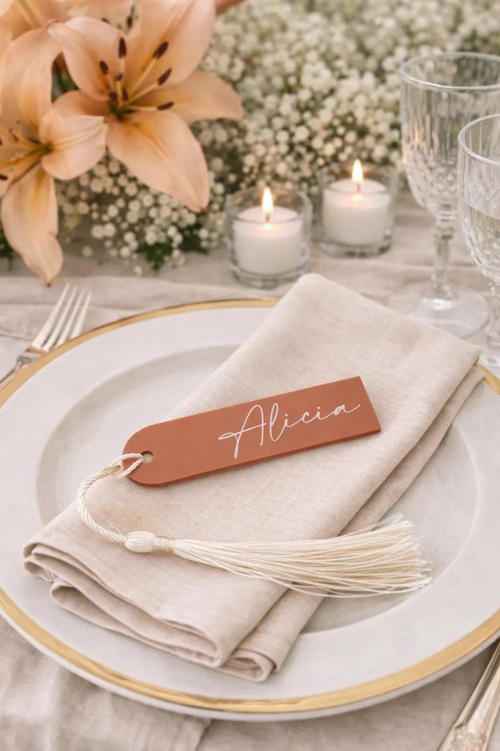 a table setting with a white plate, a napkin with a name tag, and a floral arrangement in the background.