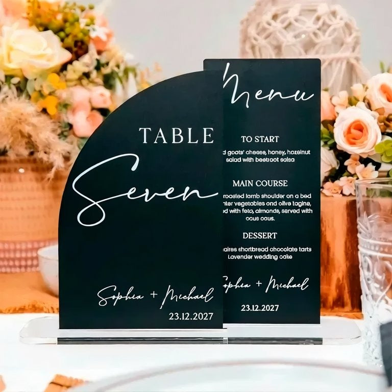 a black and white menu sign for a table, displaying the names of the courses and the names of the couple.