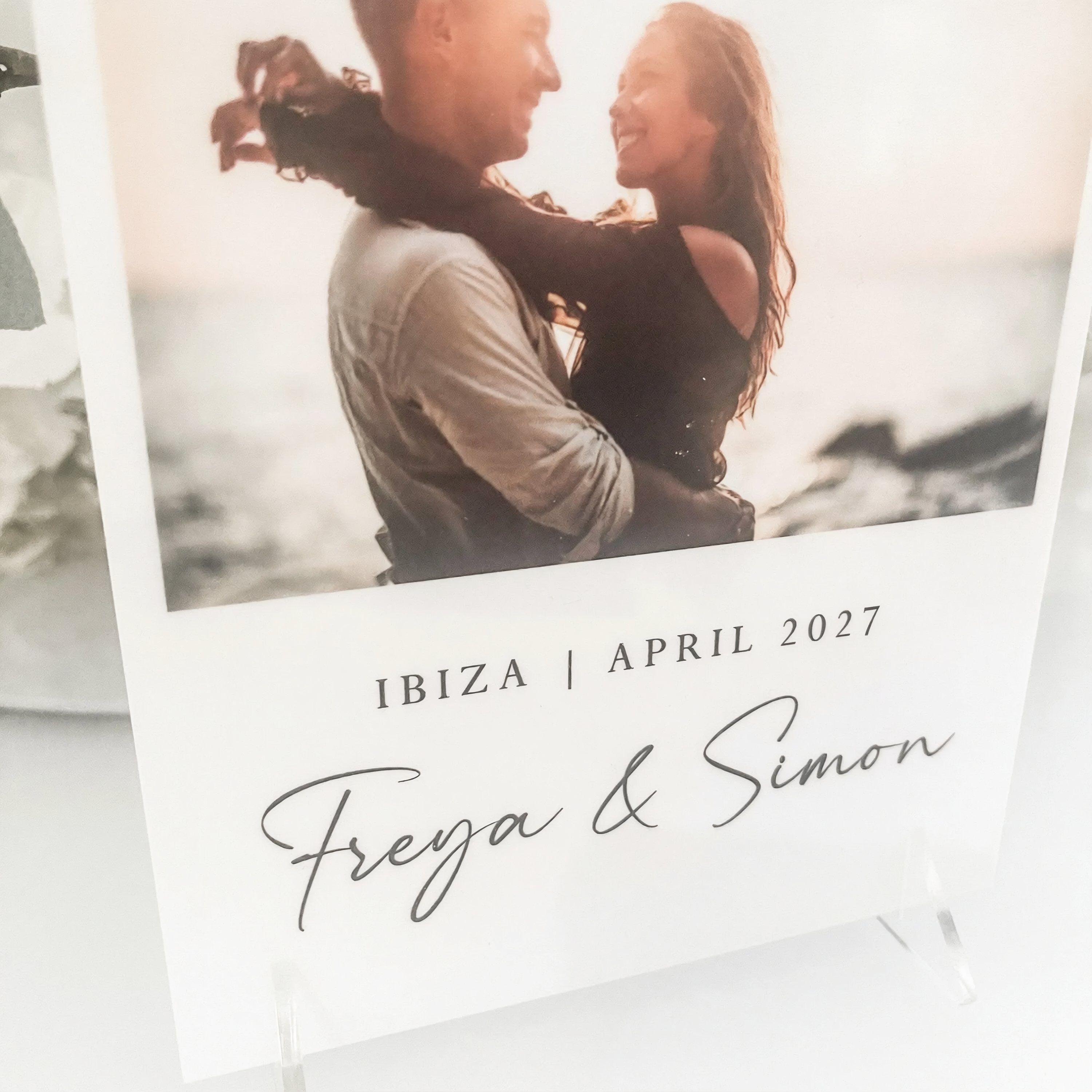 a couple embracing in a romantic setting, with the text "IBIZA | APRIL 2027" and "Freya & Simon" written below the photograph.