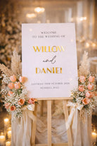 a wedding welcome sign with the names 'Willow' and 'Daniel' on it, surrounded by flowers and candles.